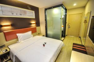 una camera da letto con un grande letto bianco e una porta in vetro di 7Days Premium Qinghuangdao Hebei Avenue Sidaoqiao Branch a Qinhuangdao