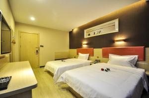 una camera d'albergo con due letti con lenzuola bianche di 7Days Premium Qinghuangdao Hebei Avenue Sidaoqiao Branch a Qinhuangdao