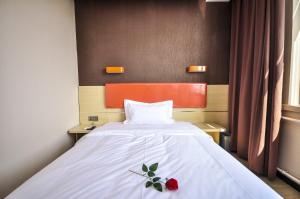 ein Schlafzimmer mit einem Bett mit einer roten Blume darauf in der Unterkunft 7Days Premium Qinghuangdao Hebei Avenue Sidaoqiao Branch in Qinhuangdao