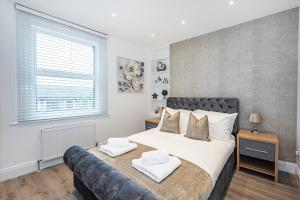 a bedroom with a large bed with a leather couch at Cozy and Serene brand-new flat in Kilburn, London in London