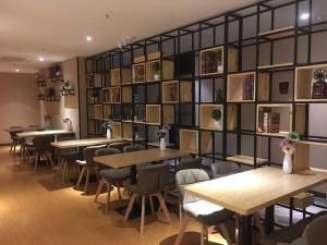 a restaurant with tables and chairs and a wall of books at 7Days Premium Chongqing Qijiang District Government Branch in Qijiang