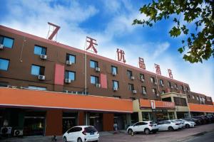 un hotel con coches aparcados delante en 7Days Premium Baoding Qingyuan Jianshe North Road Branch, en Baoding