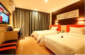 a hotel room with two beds and a flat screen tv at 7Days Premium Guang'an Chaoyang Avenue Branch in Guang'an