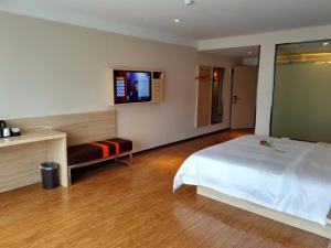 a bedroom with a white bed and a tv on the wall at 7Days Premium Chongqing Baishiyi Hot Spring Capital Branch in Chongqing