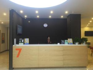 a woman standing at a counter in an office at 7Days Premium Shenyang Olympic Sports Center Subway Station Branch in Shenyang