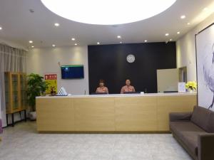 twee vrouwen aan een balie in een lobby bij 7Days Premium Delingha Center Plaza Branch in Delingha