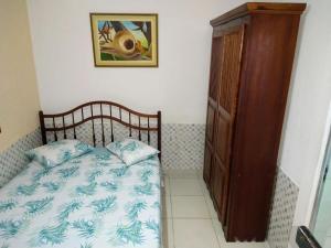 Schlafzimmer mit einem Bett und einem Holzschrank in der Unterkunft Suíte 10 com wifi a 4 min da praia em Caraguá in Caraguatatuba