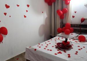 ein Schlafzimmer mit roten Herzen an der Wand und ein Bett mit Ballons in der Unterkunft Suíte 3 com wifi a 4 min da praia em Caraguatatuba in Caraguatatuba