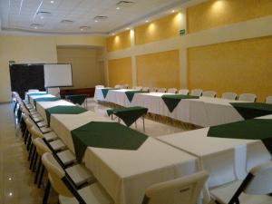 a conference room with tables and chairs and a screen at Hotel Las Fuentes in Los Mochis
