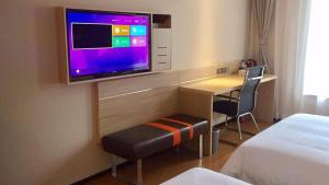 Habitación de hotel con TV, escritorio y cama en 7Days Premium Chongqing Dazu Shike XIncheng Branch, en Dazu