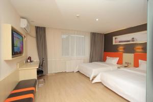 um quarto de hotel com duas camas e uma televisão de ecrã plano em 7Days Premium Beidaihe Dove Nest Park Branch em Qinhuangdao