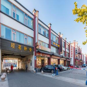 un grand bâtiment avec des voitures garées devant lui dans l'établissement 7Days Premium Beijing Happy Valley Wangsiyingqiao Branch, à Pékin