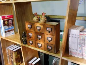 a shelf with a wooden cabinet with books and rabbits on it at 7Days Premium Xingtai Railway Station Tianyi Street Branch in Xingtai