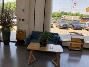 a living room with a blue couch and a table at 7Days Premium Nanchang Liantang Yingbin Middle Avenue Xiaolan Industrial Park Branch in Nanchang