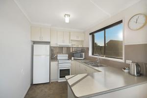 a kitchen with white appliances and a clock on the wall at Eagle Heights Holiday Units in Eden