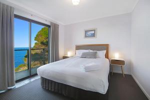 a bedroom with a large bed and a large window at Eagle Heights Holiday Units in Eden