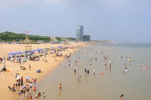 un gran grupo de personas en una playa en 7Days Premium Laizhou City Government Branch, en Laizhou