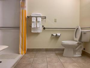 a bathroom with a toilet and a shower and towels at Rincon Inn and Suites in Rincon