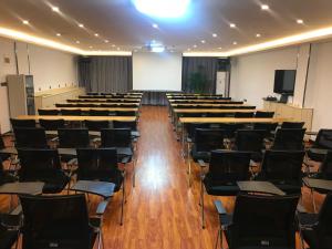 una sala de conferencias con sillas, una pantalla y un podio en 7Days Premium Zibo Huantai Xinyu Building Branch, en Zibo