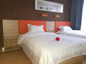 a bedroom with two beds with a red rose on it at 7Days Premium Yancheng Dafeng Zhongjiao Meilucheng Branch in Yancheng