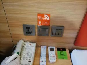 un mando a distancia y otros aparatos electrónicos sobre una mesa en 7Days Premium Luoyang Peony Park Shanghai Market Branch, en Luoyang