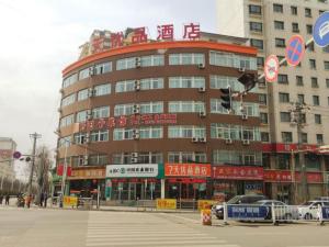 - un grand bâtiment dans une rue avec des voitures devant dans l'établissement 7Days Premium Dingxi Train Station Branch, à Dingxi