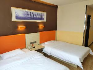 a room with two beds and a phone in it at 7Days Premium Dingxi Train Station Branch in Dingxi +12 photos