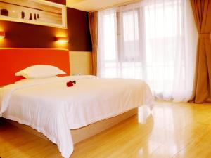 Un dormitorio con una cama blanca con una rosa roja. en 7Days Premium Jinan West Railway Station Branch, en Jinan