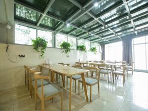 uma sala de jantar com mesas, cadeiras e janelas em 7Days Premium Chongqing West Station Branch em Chongqing