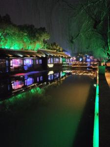 a night view of a building with green and purple lights at 7Days Premium Suzhou Tongli Ancient Town Branch in Suzhou