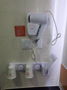 a hair dryer and a phone on a wall at 7Days Premium Suzhou Tongli Ancient Town Branch in Suzhou