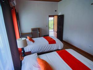 a hotel room with two beds with red and white sheets at Mar Inn Costa Rica in Monteverde Costa Rica
