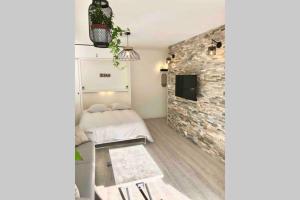 1 dormitorio con cama y pared de piedra en Grand studio cabine 30 m² centre ville, refait à neuf pour vous ! Climatisé, en La Grande-Motte