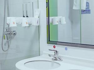 uma casa de banho com um lavatório e um espelho em 7Days Premium Xiamen Airport Xianglu Branch em Xiamen