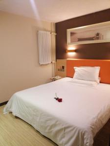 a bedroom with a white bed with a rose on it at 7Days Premium Qingdao Xianggang Middle Road Zhiqun Road Subway Station Branch in Qingdao