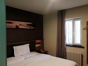 a bedroom with a bed and a window at 7Days Premium Harbin Central Street Sophia Church Branch in Harbin