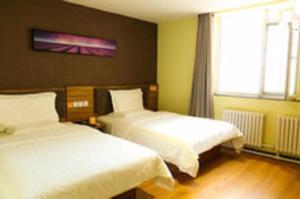 a hotel room with two beds and a window at 7Days Premium Harbin Central Street Sophia Church Branch in Harbin