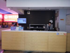a man standing behind a counter in a restaurant at 7Days Premium Zunyi Dingzikou Branch in Zunyi