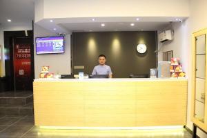 海口市にある7Days Premium Haikou Pearl Plaza Wuzhishan Road Branchの店のカウンターに座る男