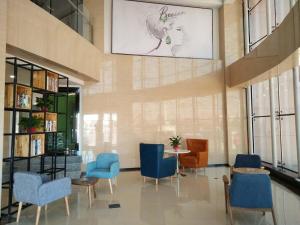 a lobby with chairs and a table and a drawing on the wall at 7Days Premium Shandan Center Plaza Branch in Zhangye