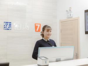 a woman standing at a desk with a computer at 7Days Premium Shandan Center Plaza Branch in Zhangye