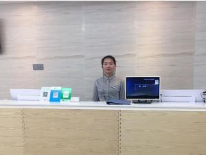 a woman standing behind a desk with a computer at 7Days Premium Yantai Railway Station Branch in Yantai