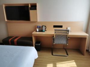 7Days Premium Hengshui Shenzhou City Government Branch في Hengshui: غرفة في الفندق مع مكتب مع سرير وتلفزيون