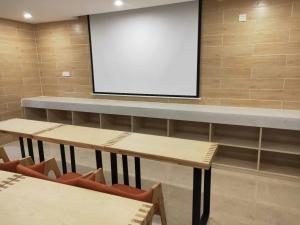 a lecture room with two tables and a projection screen at 7Days Premium Guangzhou Chenjiaci Dukang Avenue in Guangzhou