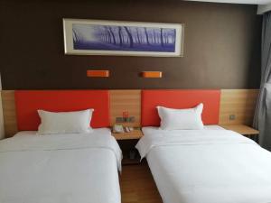 duas camas num quarto com vermelho e branco em 7Days Premium Luoyang Yichuan Dukang Avenue Branch em Luoyang