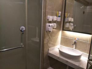 a bathroom with a shower with a sink and a mirror at 7Days Premium Xining Bayi East Road Tuanjie Bridge Branch in Xining