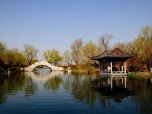 een prieel in het midden van een meer met een brug bij 7Days Premium Jinan Beiyuan Street Red Star Macalline Branch in Jinan