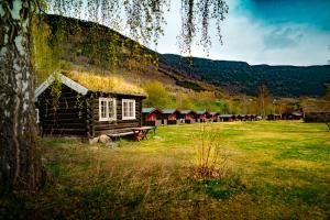 Kirketeigen Camping في Kvam: كابينة خشب قديمة في حقل من العشب