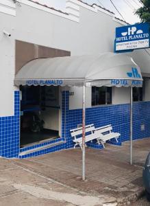 a blue and white building with a bench in front of it at Hotel Planalto in Poços de Caldas