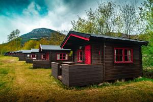 a row of wooden cabins with red windows in a field at Kirketeigen Camping in Kvam